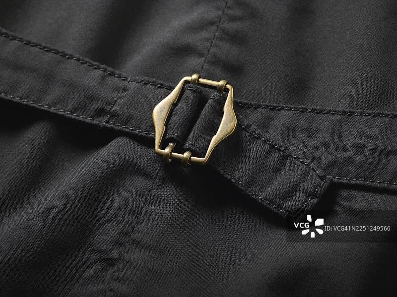 深色织物上黄铜搭扣的特写，带有细致的缝线图片素材