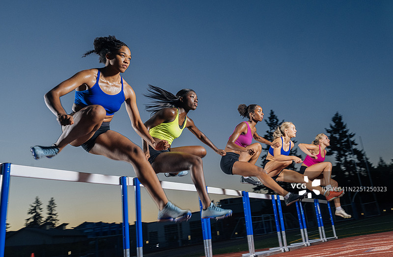 华盛顿州，美国。运动员在黄昏的训练中在户外赛道上跳过栏架。图片素材