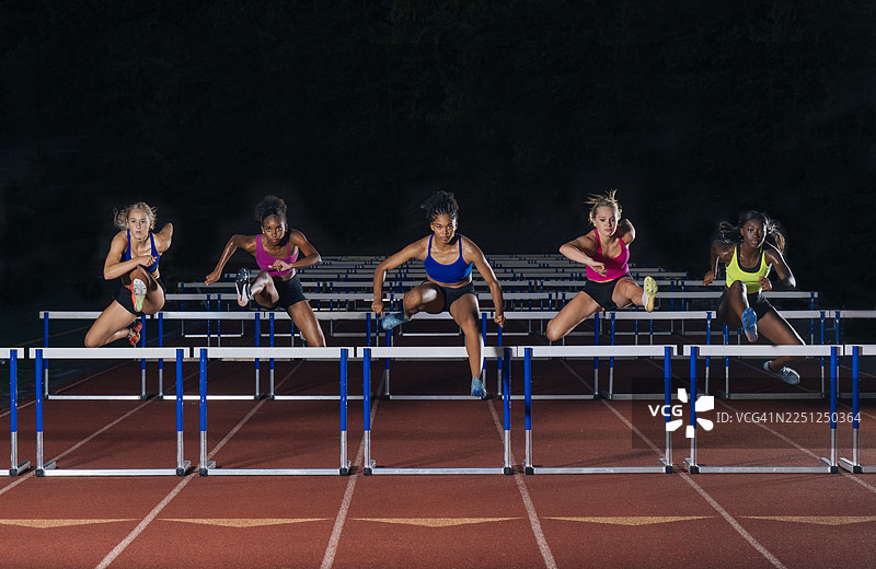 四名身着鲜艳运动服的运动员同步跳过田径栏。美国华盛顿州图片素材