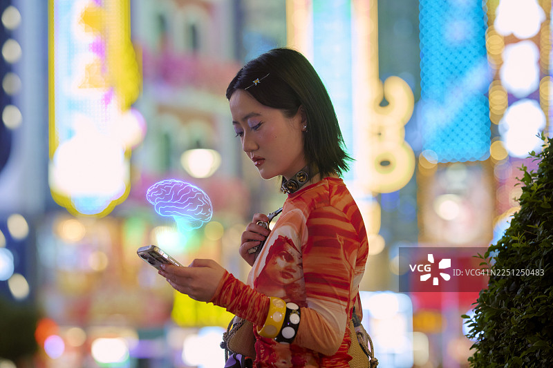 一位年轻成年人在背景为充满活力的城市灯光的上海中国使用新款人工智能智能手机。图片素材