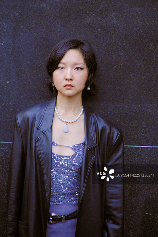 身着优雅服饰、佩戴珍珠项链的年轻女子，背景为上海的黑暗环境图片素材