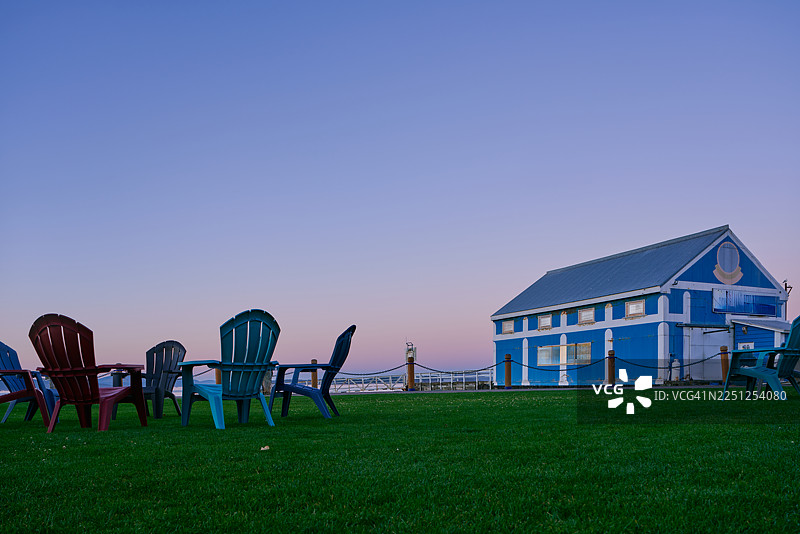 日落时分，五颜六色的草坪椅面向蓝色滨水建筑图片素材