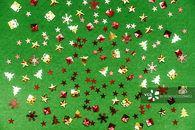明亮的绿色背景上的五彩纸屑圣诞装饰，带有礼物、星星、雪花和圣诞树图片素材