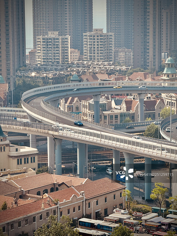 高角度俯瞰现代城市，多层高速公路穿梭于居民楼和高耸的摩天大楼之间，天空灰蒙蒙的，中国图片素材