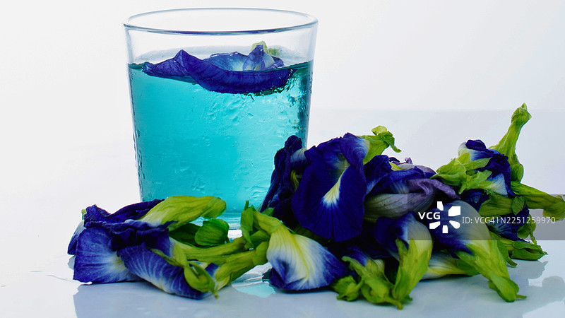 白色背景上鲜花盛开的鲜艳蓝蝴蝶花茶，展示出天然色彩和健康饮品的概念图片素材