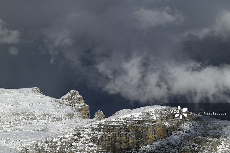 从低角度戏剧性地拍摄，展示了乌云密布的天空下的雪山，唤起了原始自然和冬季宏伟的感觉，意大利，利维纳尔隆戈-迪尔科尔-迪拉纳，波尔多伊山口图片素材