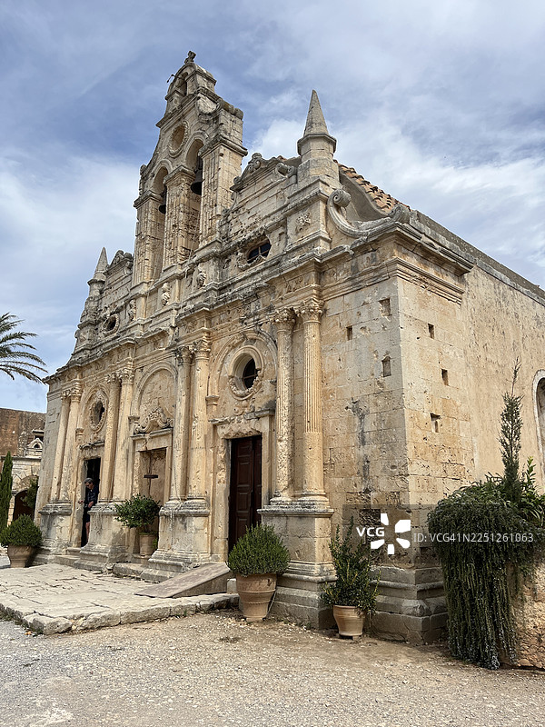 低角度拍摄的古老石头教堂，背景是多云的天空，展示了历史建筑和宗教遗产，希腊图片素材