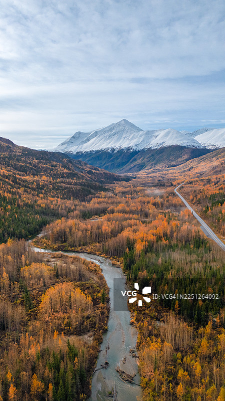壮丽的航拍景象，蜿蜒的河流穿过充满活力的秋季森林，背景是白雪皑皑的山脉，美国，瓦尔迪兹图片素材