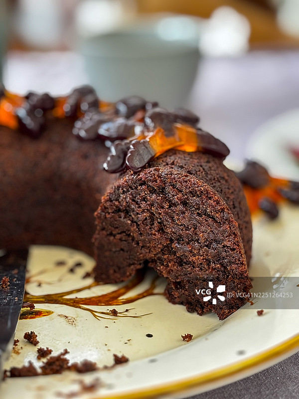 美味的手工巧克力蛋糕，切下一片，展示其丰富的质地和装饰盘上的甜美顶料图片素材