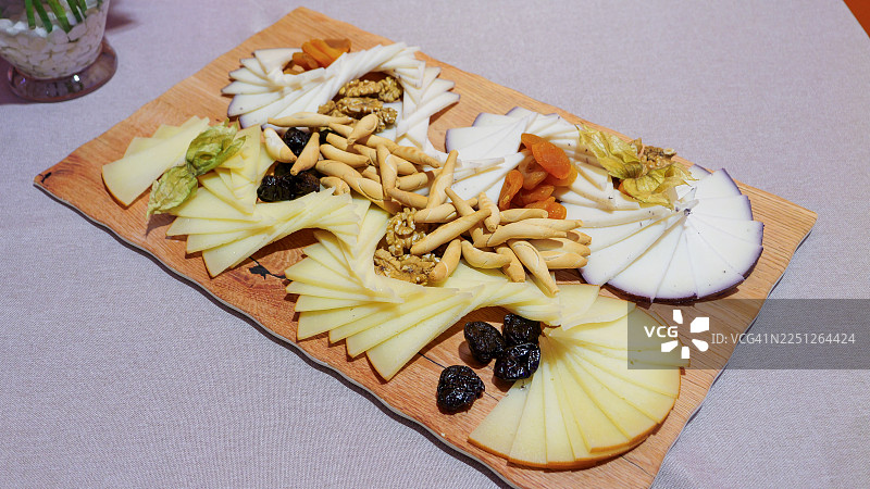 从高处俯瞰美味的奶酪拼盘，上面有各种奶酪、干果、坚果和面包棒，非常适合招待客人或作为美食小吃。图片素材