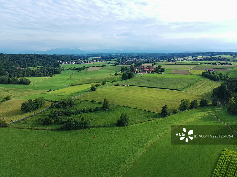 俯瞰郁郁葱葱的绿色农田和村庄，天空布满云彩，展现出乡村景观和自然风光图片素材