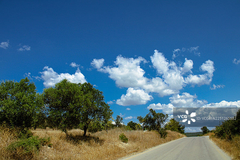 土耳其吉里波鲁，蓝天白云下，绿树与干草间的空旷道路图片素材