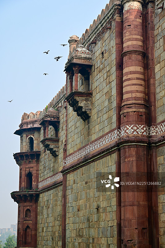 从低角度拍摄的古老堡垒城墙，带有装饰性阳台和飞鸟，背景是晴朗的天空，地点：印度新德里，普拉纳·基拉图片素材