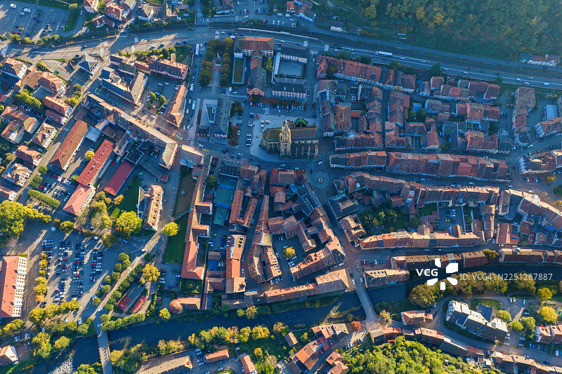 一座迷人的欧洲小镇的鸟瞰图，有历史悠久的教堂和蜿蜒的河流，周围环绕着秋天的树木图片素材