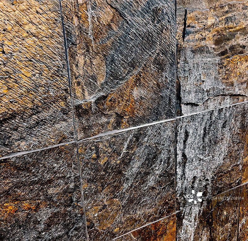 特写全景镜头，展示了风化的石墙，其纹理和颜色各不相同，展现出自然的图案和粗犷的美感图片素材