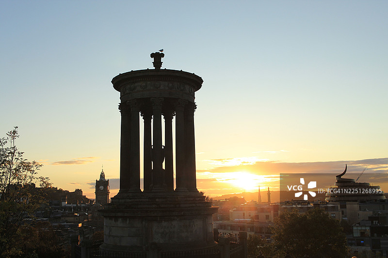 历史古城的戏剧性日落天际线，有剪影纪念碑和远处的钟楼图片素材