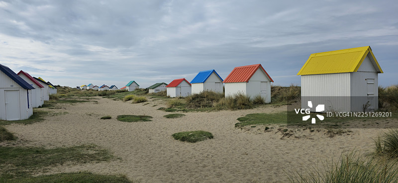 色彩缤纷的海滩小屋排列在沙滩上，天空多云，营造出一种海岸魅力和宁静感，法国，Rue du Beau Rivage图片素材
