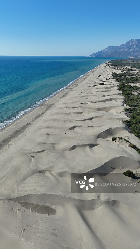 蔚蓝大海与沙丘交汇的原始海滩的鸟瞰图，天空湛蓝图片素材