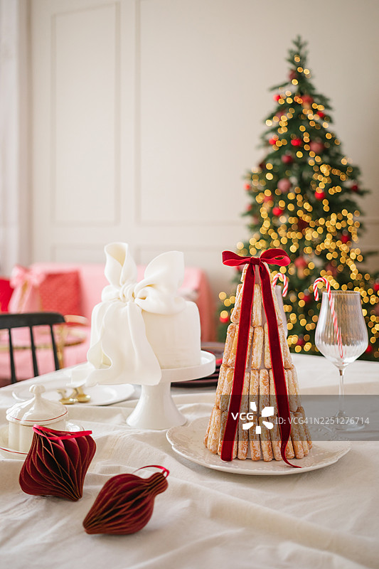 圣诞树灯光前餐桌上的手指饼干泡芙塔甜点图片素材