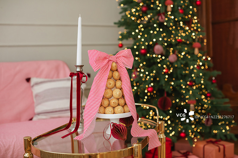 餐桌上摆放着克罗肯布什风格的甜点和传统斯托伦水果蛋糕，背景是亮灯的圣诞树。图片素材