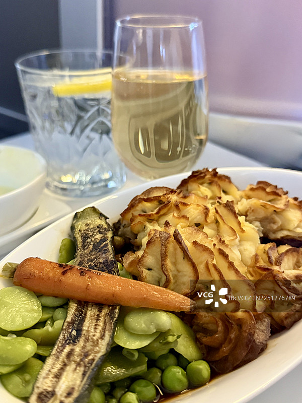 飞机餐特写，包含牧羊人派、什锦蔬菜，配有香槟和水图片素材