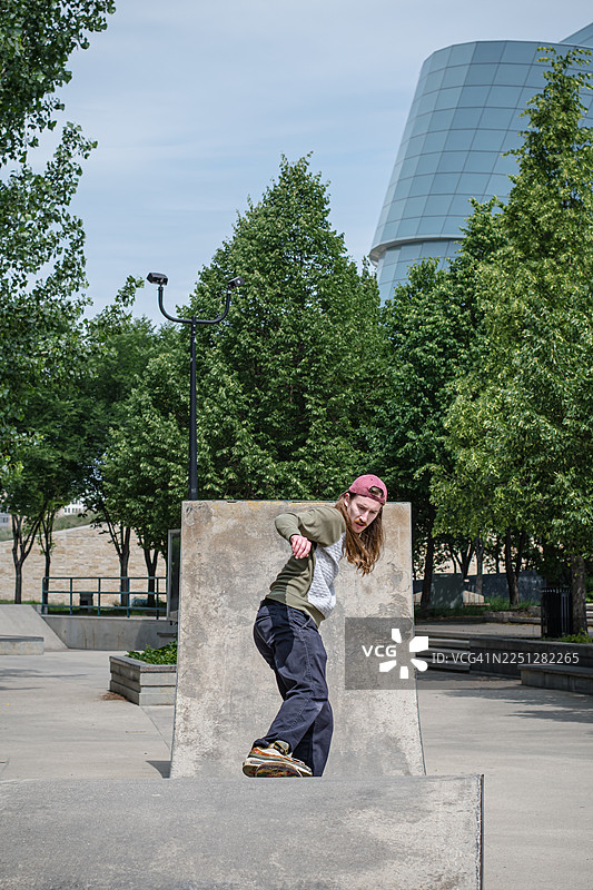 在风景优美的背景下，一位滑板运动员正在垂直滑道上滑行图片素材