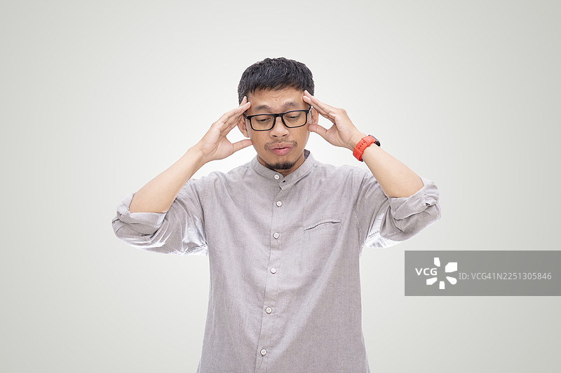 亚洲年轻男子在白色背景下手扶额头，做出压力手势图片素材