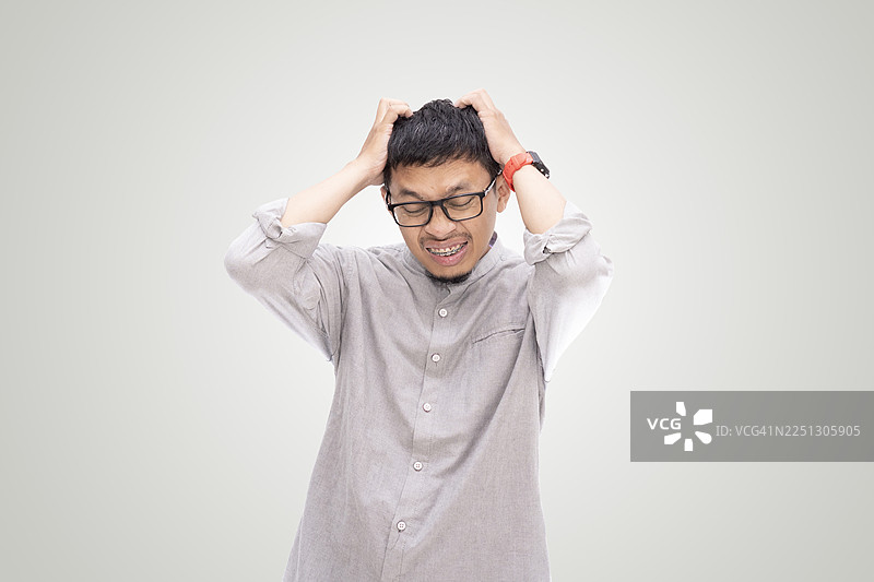 亚洲年轻男子用手摸着额头，在白色背景上做出压力手势图片素材