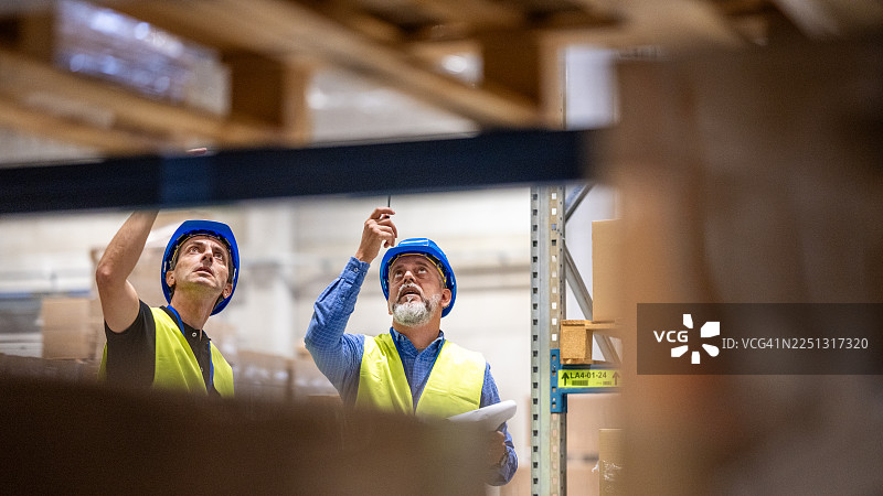 穿着安全装备的工人在检查仓库设备图片素材