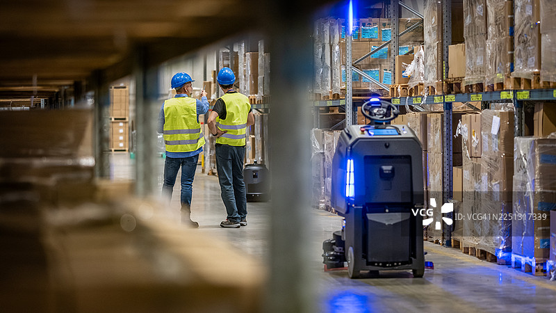 穿着高能见度背心和安全帽的工人在仓库里图片素材