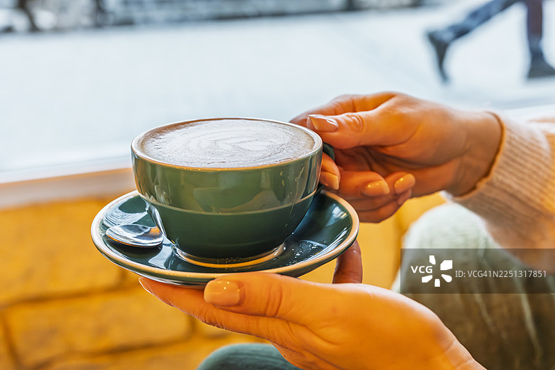 手持一杯拉花拿铁，温暖惬意图片素材