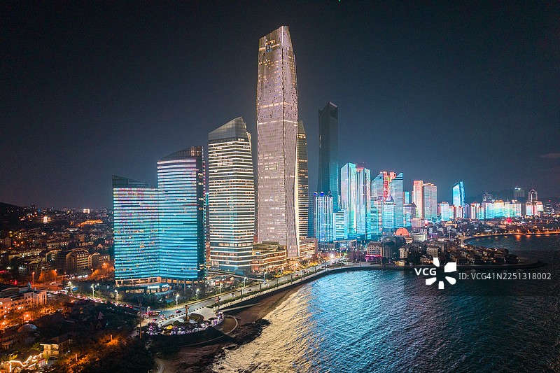 傍晚时分，中国山东青岛第三海水浴场上方的城市天际线被鲜艳的灯光点亮。图片素材