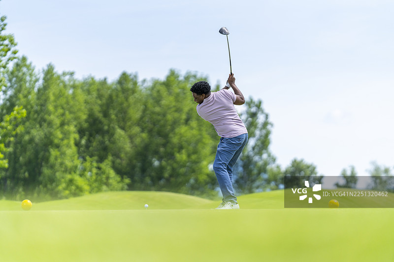 年轻的西班牙裔男性高尔夫球手在风景优美的球场上挥动一号木杆图片素材
