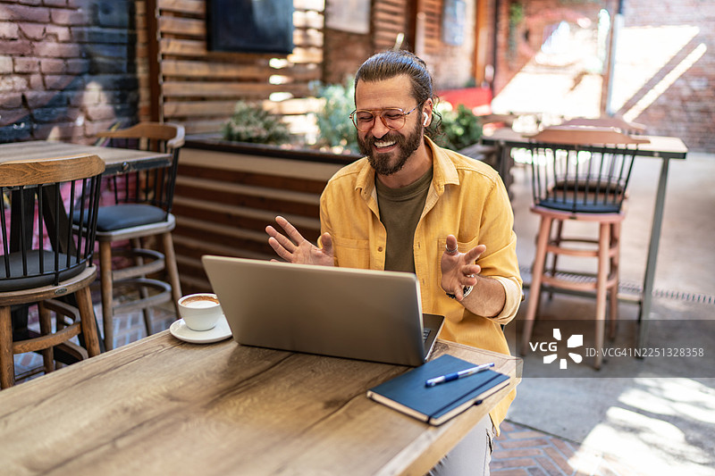 男人在户外咖啡馆用笔记本电脑进行视频通话图片素材