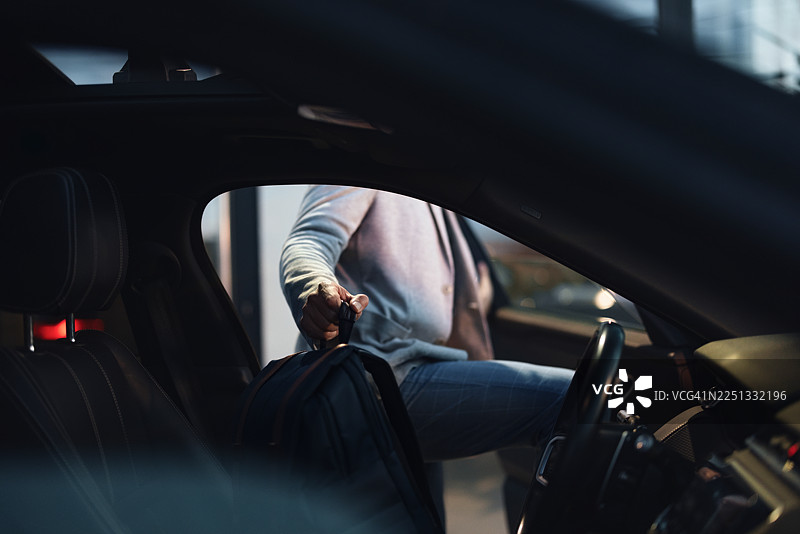男子在车内，带着笔记本电脑包，在晚上抓起钥匙，准备去上班图片素材