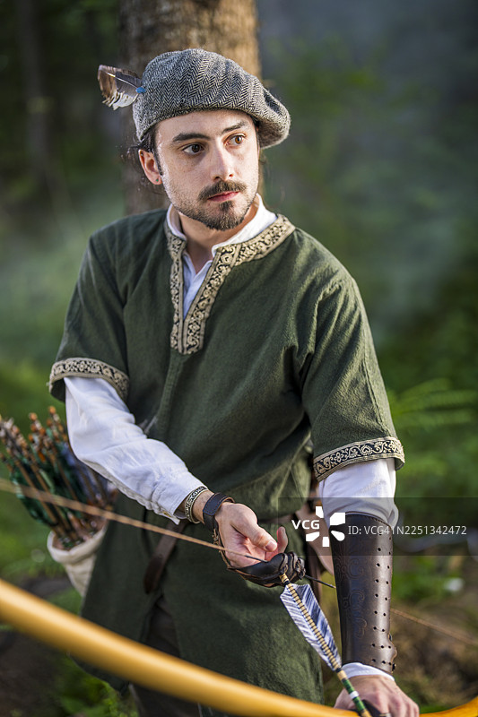 身穿中世纪服装的年轻高加索弓箭手在森林中持弓图片素材