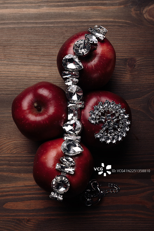 俯视视角，红苹果放在木桌上，上面摆放着一套装饰性珠宝图片素材
