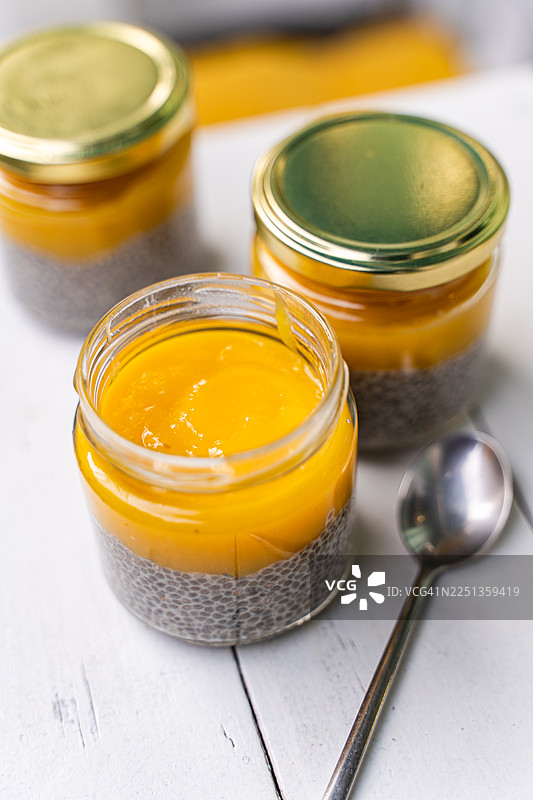 花园桌上三个玻璃罐的特写，里面装着奇亚籽布丁和芒果甜点图片素材