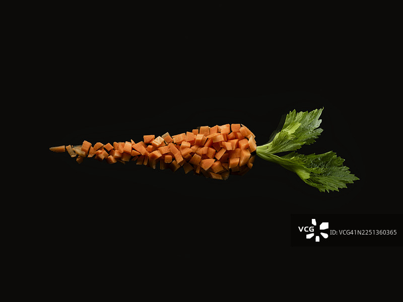 黑色背景上切成块状的胡萝卜，形状像一整根胡萝卜图片素材