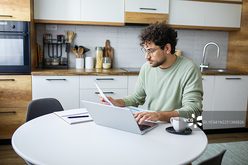 专注的男士使用笔记本电脑填写税务表格图片素材