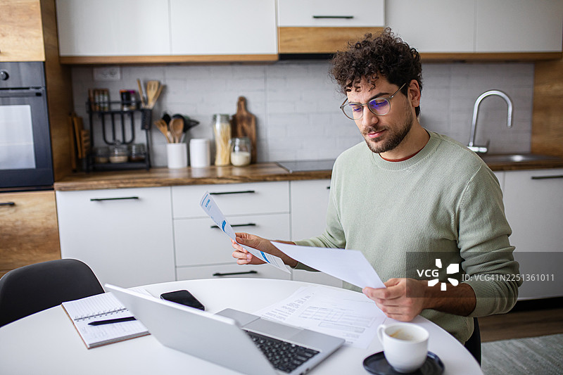 专注的男士使用笔记本电脑填写税务表格图片素材