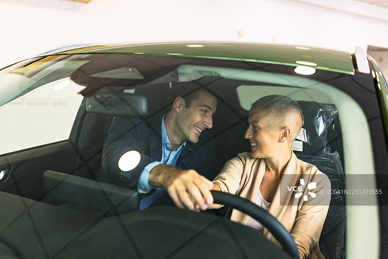 一对快乐的夫妇在汽车经销商处一起购买新车，脸上洋溢着笑容图片素材