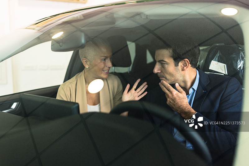 一对幸福的夫妇正在汽车经销商处讨论购买新车图片素材