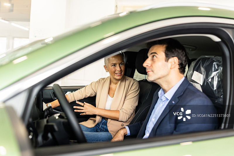 汽车销售员和男顾客坐在车内讨论功能图片素材
