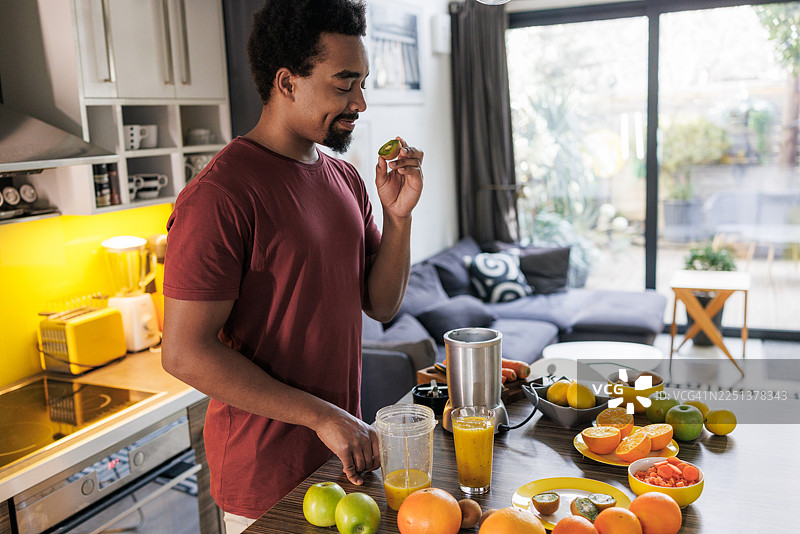 年轻男子在现代家庭厨房里准备新鲜水果汁图片素材