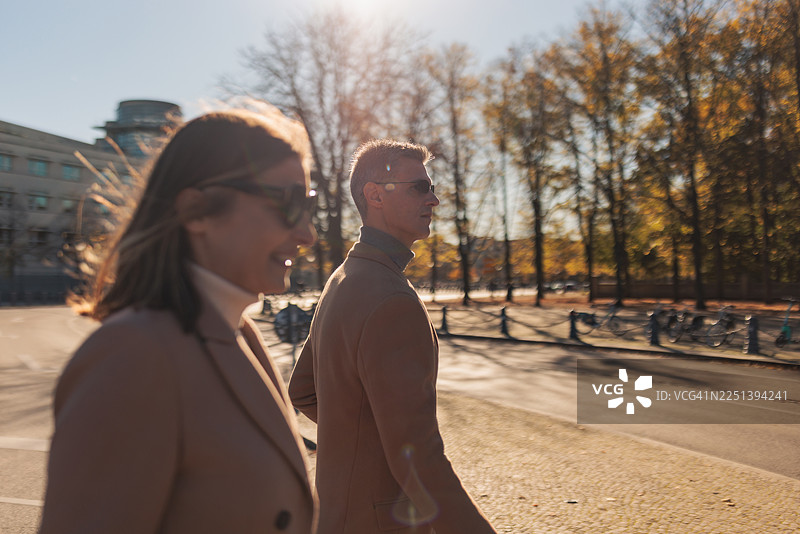 阳光明媚的秋日，一对情侣漫步在城市中图片素材
