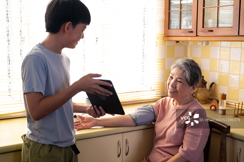 亚洲孙子在厨房帮助奶奶测量血压图片素材