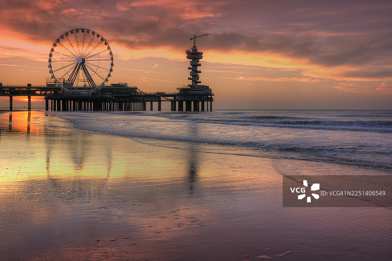 夕阳下的斯海弗宁恩码头倒映在湿沙上图片素材