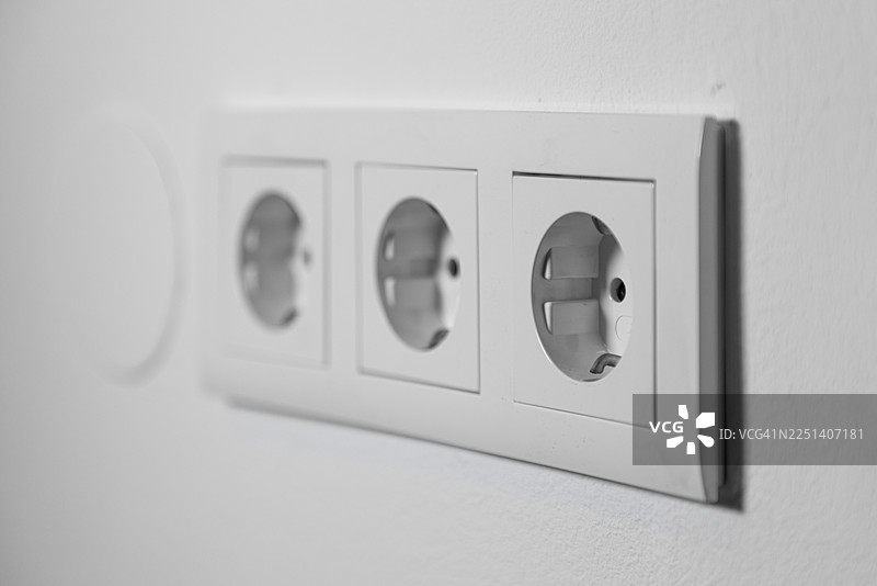 白色墙壁上的白色三孔插座图片素材