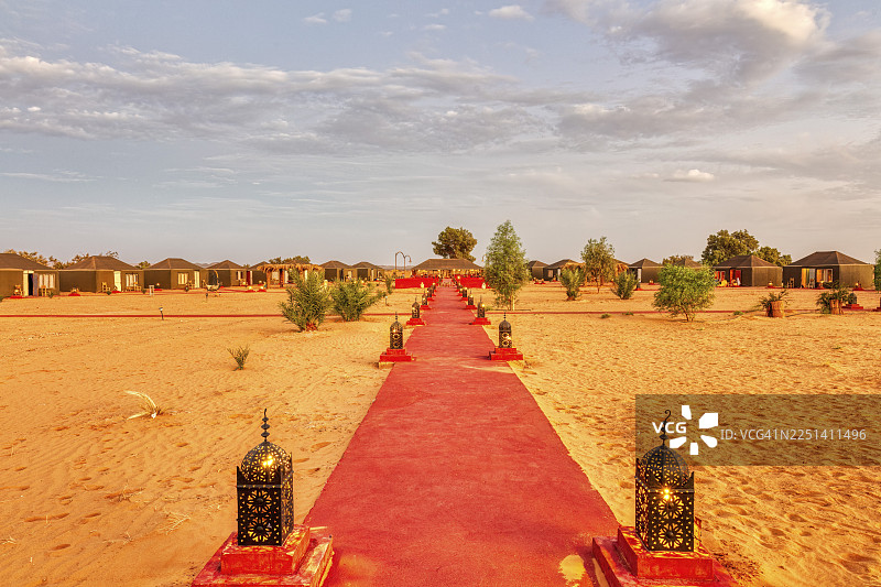 摩洛哥撒哈拉沙漠中的红色地毯小径，两旁点缀着灯笼，通向帐篷。图片素材